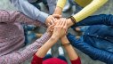 Stronger together: people joining hands in a huddle