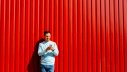 Mann mit Handy vor rotem Hintergrund