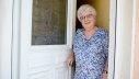 Alte Frau steht an offener Haustür