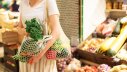 Frau kauft Obst und Gemüse im Geschäft mit einem Netzbeutel