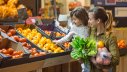 Kind geht mit Mutter im Supermarkt Obst und Gemüse einkaufen