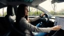 Frau im Fahrerinnensitz tippt auf Touchscreen im Auto.