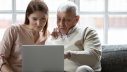 junge Frau und alter Mann benutzen Laptop gemeinsam