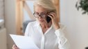 Frau telefoniert und blickt auf Dokument