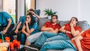 Gelangweilte junge Leute schauen auf einem Sofa TV