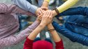 Stronger together: people joining hands in a huddle