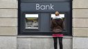 Junge Frau holt bei einer Bank Geld am Geldautomaten