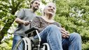 Sohn schiebt seine demenzkranke Mutter im Rollstuhl