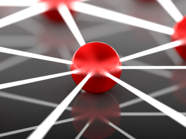 Zu sehen ist ein abstrakt dargestelltes Netzwerk. Auf dunklem Grund sind rote Kugeln jeweils mit weißen Linien verbunden. Der Ausschnitt spiegelt sich zudem in dem dunklen Untergrund. 