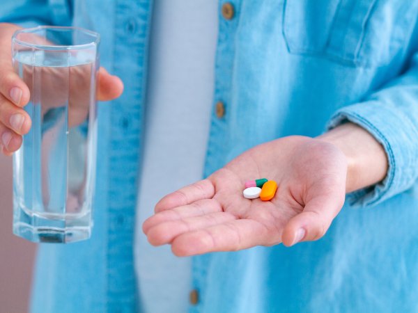 Glas Wasser und Tabletten in der Hand