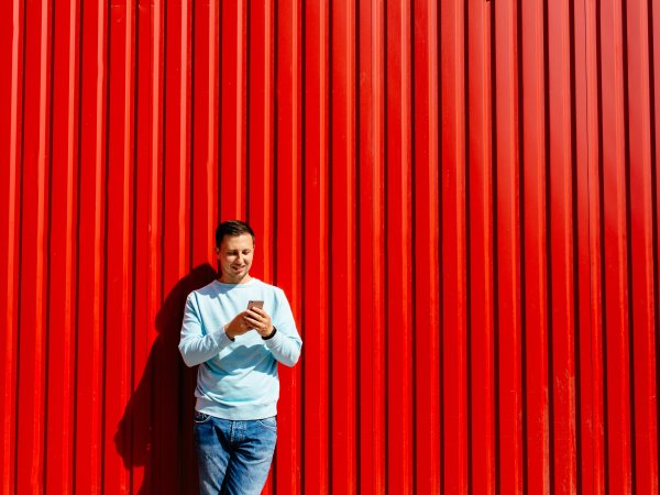 Mann mit Handy vor rotem Hintergrund