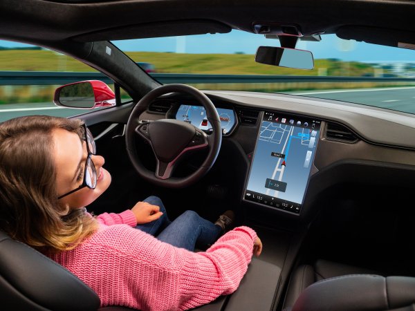 Frau sitzt in einem autonom fahrenenden Auto.