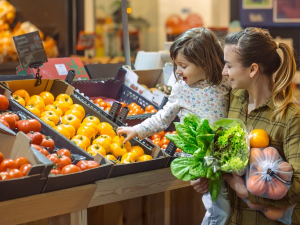 Kind geht mit Mutter im Supermarkt Obst und Gemüse einkaufen