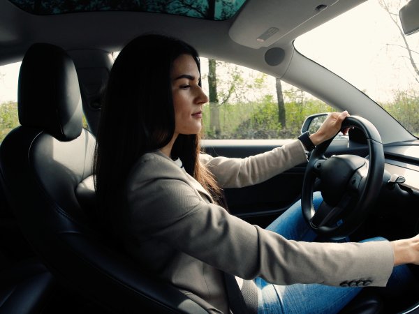 Frau im Fahrerinnensitz tippt auf Touchscreen im Auto.