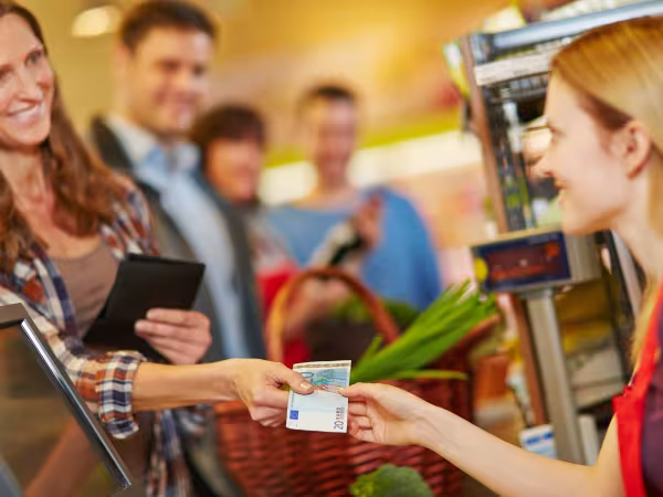 Frau bezahlt an der Kasse mit Bargeld