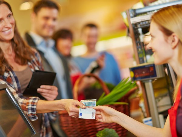 Frau bezahlt an der Kasse mit Bargeld