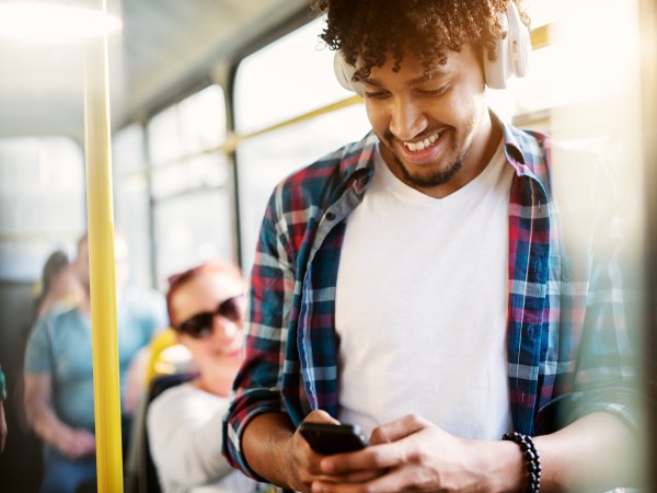 Mann in Bus schaut lächelnd auf sein Handy