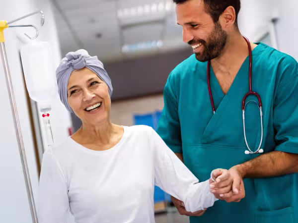 lächelnde Frau wird in Krankenhaus von Pfleger gestützt