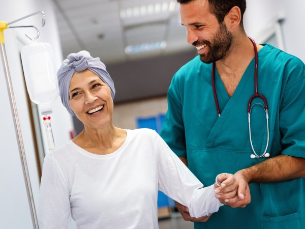 lächelnde Frau wird in Krankenhaus von Pfleger gestützt