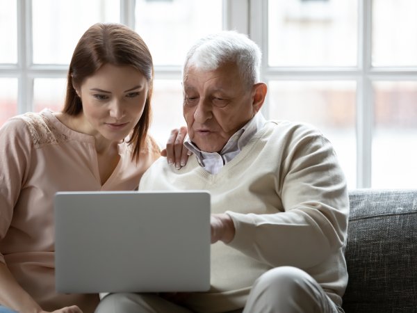 junge Frau und alter Mann benutzen Laptop gemeinsam