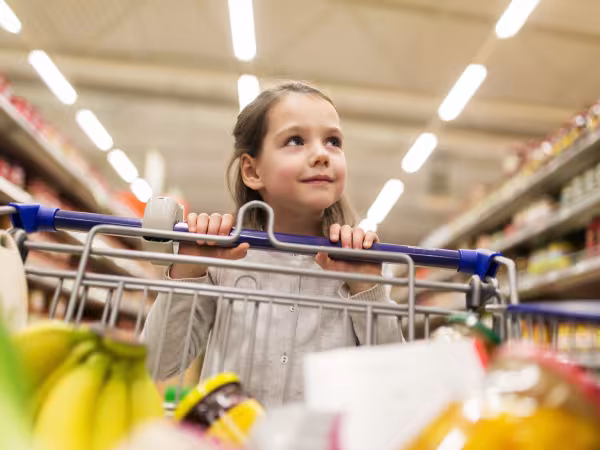 Mädchen mit Einkaufswagen im Supermarkt