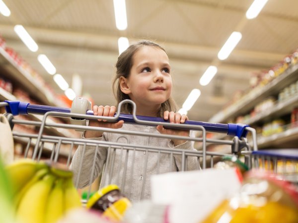 Mädchen mit Einkaufswagen im Supermarkt