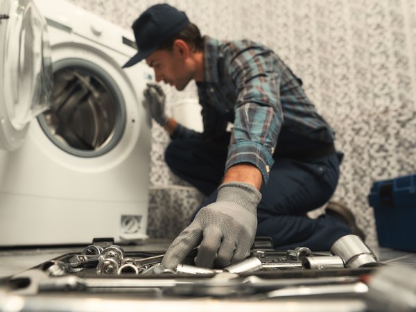 Mann repariert Waschmaschine