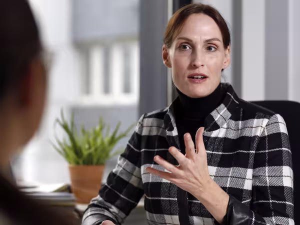 Zu sehen ist Jutta Gurkmann an einem Schreibtisch sitzend im Gespräch. 
