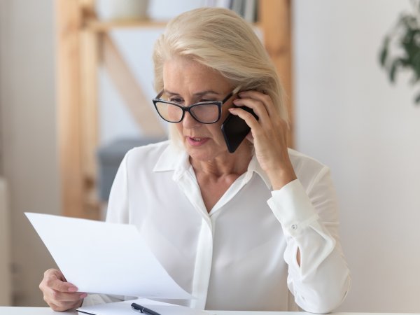 Frau telefoniert und blickt auf Dokument