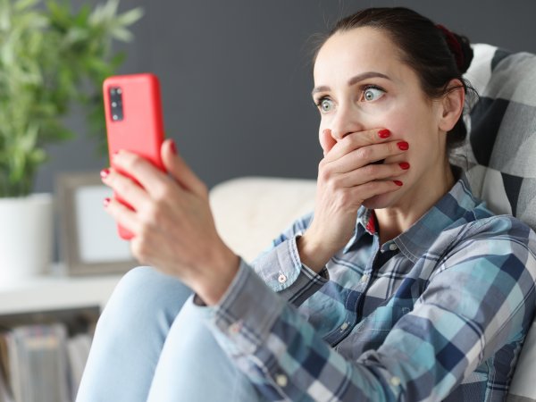 Sitzende Frau erschrickt beim Blick auf ihr Handy