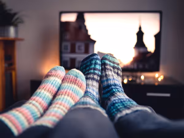 Paar mit Socken vor Fernseher in behaglichem Zuhause