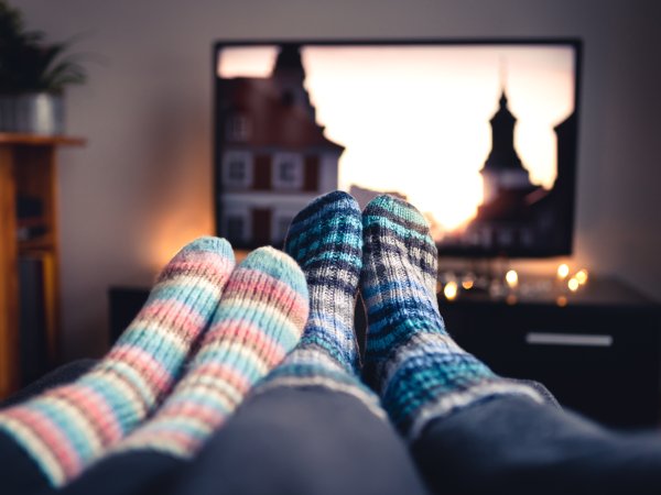 Paar mit Socken vor Fernseher in behaglichem Zuhause