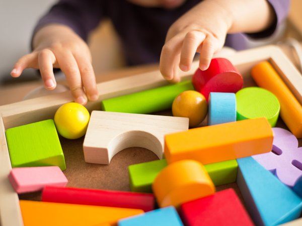 Ein Kind spielt mit bunten Bauklötzen.