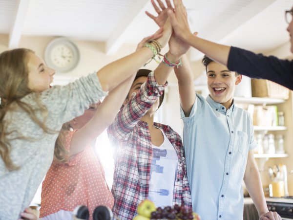 Zu sehen ist eine Gruppe von fünf Schüler:innen, die ihre Hände in der Mitte abklatschen. 