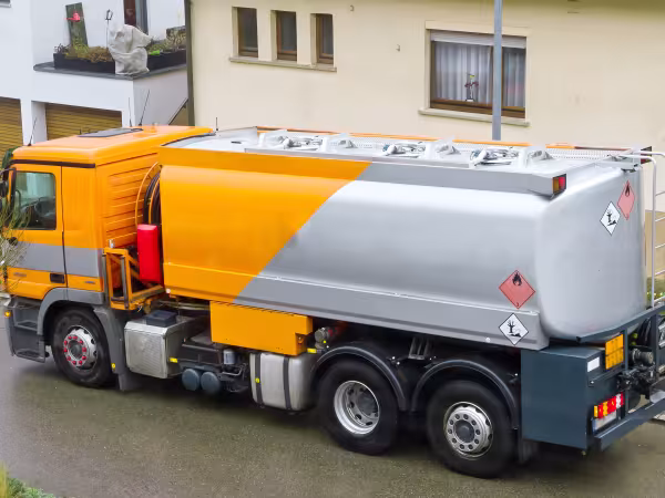 Ein Tankwagen mit Heizöl steht vor einem Mehrfamilienhaus