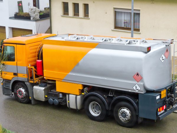 Ein Tankwagen mit Heizöl steht vor einem Mehrfamilienhaus