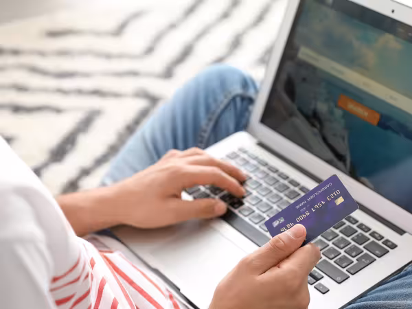 Person bucht mit Laptop und Kreditkarte Flugtickets