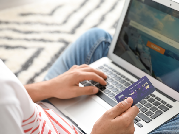Person bucht mit Laptop und Kreditkarte Flugtickets