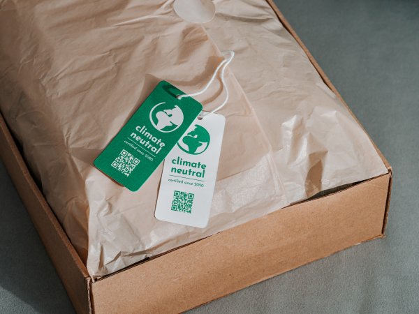 Ein Paket mit zwei Anhängern, auf denen die Klimaneutralität des Produkts beworben wird