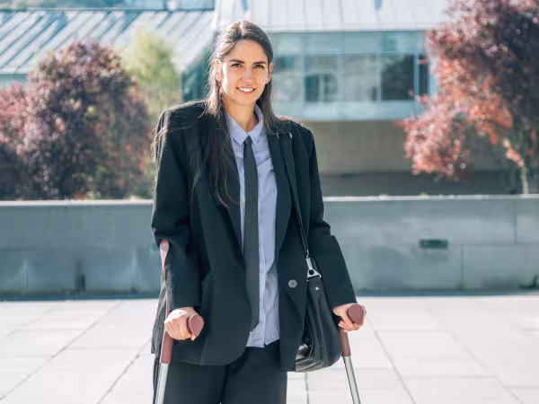Frau im Business-Outfit mit Krücken 