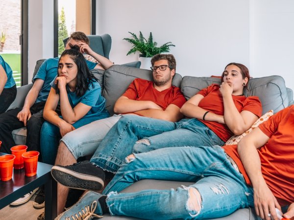 Gelangweilte junge Leute schauen auf einem Sofa TV