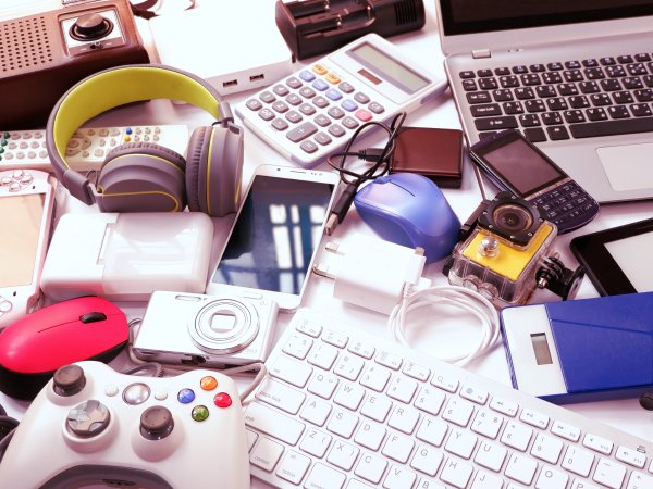 Zu sehen ist ein Ansammlung von technischen Geräten, wie Kopfhörer, Taschenrechner, Tastaturen, Mäuse, Controller, Smartphones, Kameras, Fernbedienungen.