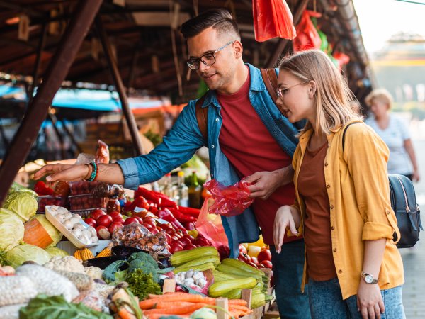 Mann und Frau betrachten Lebensmittel an einem Marktstand