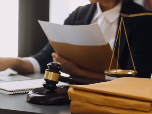 Person sitzt am Tisch; vor der Person liegt ein Richterhammer