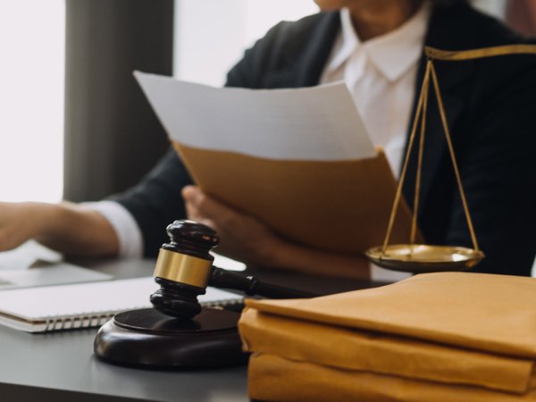 Person sitzt am Tisch; vor der Person liegt ein Richterhammer