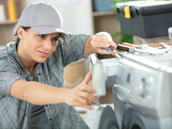 Frau repariert Waschmaschine