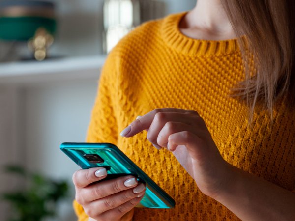 Frau blickt auf Handy, das sie in der Hand hält