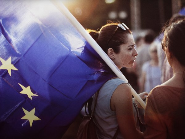 Zwei Personen stehen zusammen; eine von ihnen hält eine große EU-Flagge in der Hand