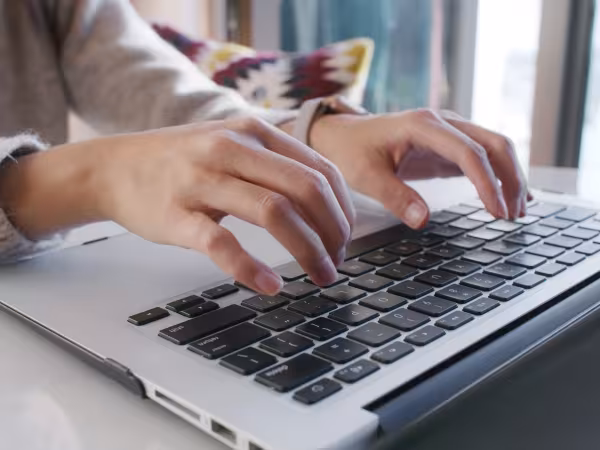 Eine Frau tippt mit den Händen am Laptop