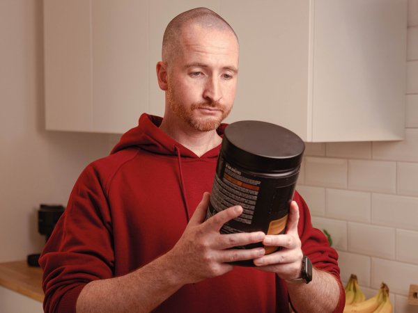 Mann hält Dose mit Proteinpulver in den Händen 